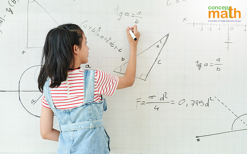 Young student writes on whiteboard filled with math diagrams