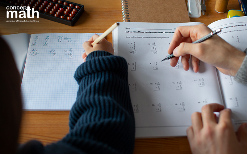 A student gets help solving a math worksheet on subtracting mixed numbers