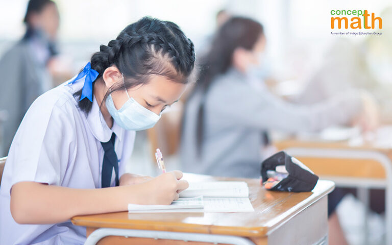 Female student with boxer braids wearing a mask, focused on taking an exam